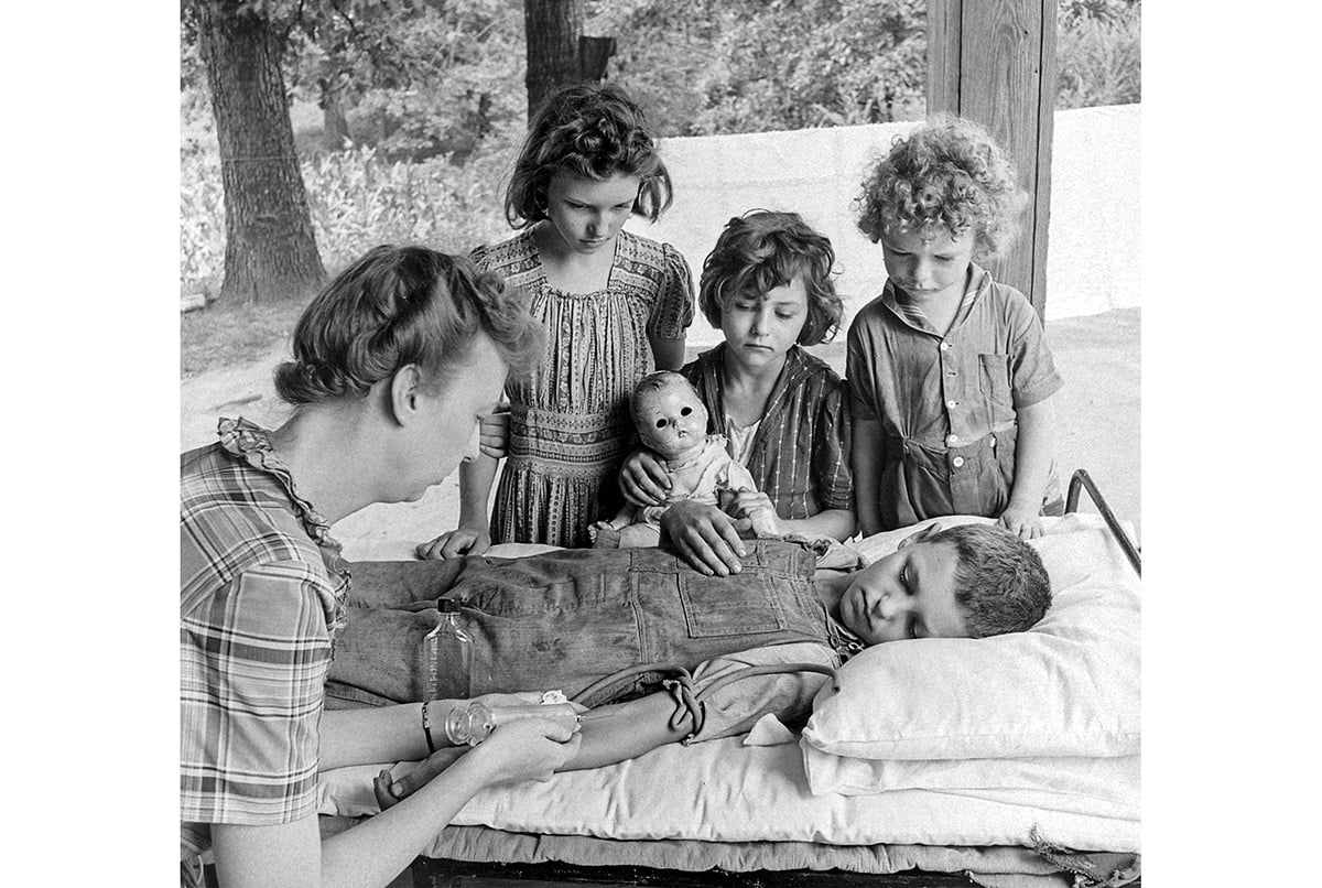A woman takes a blood sample from a boy in a polio hospital