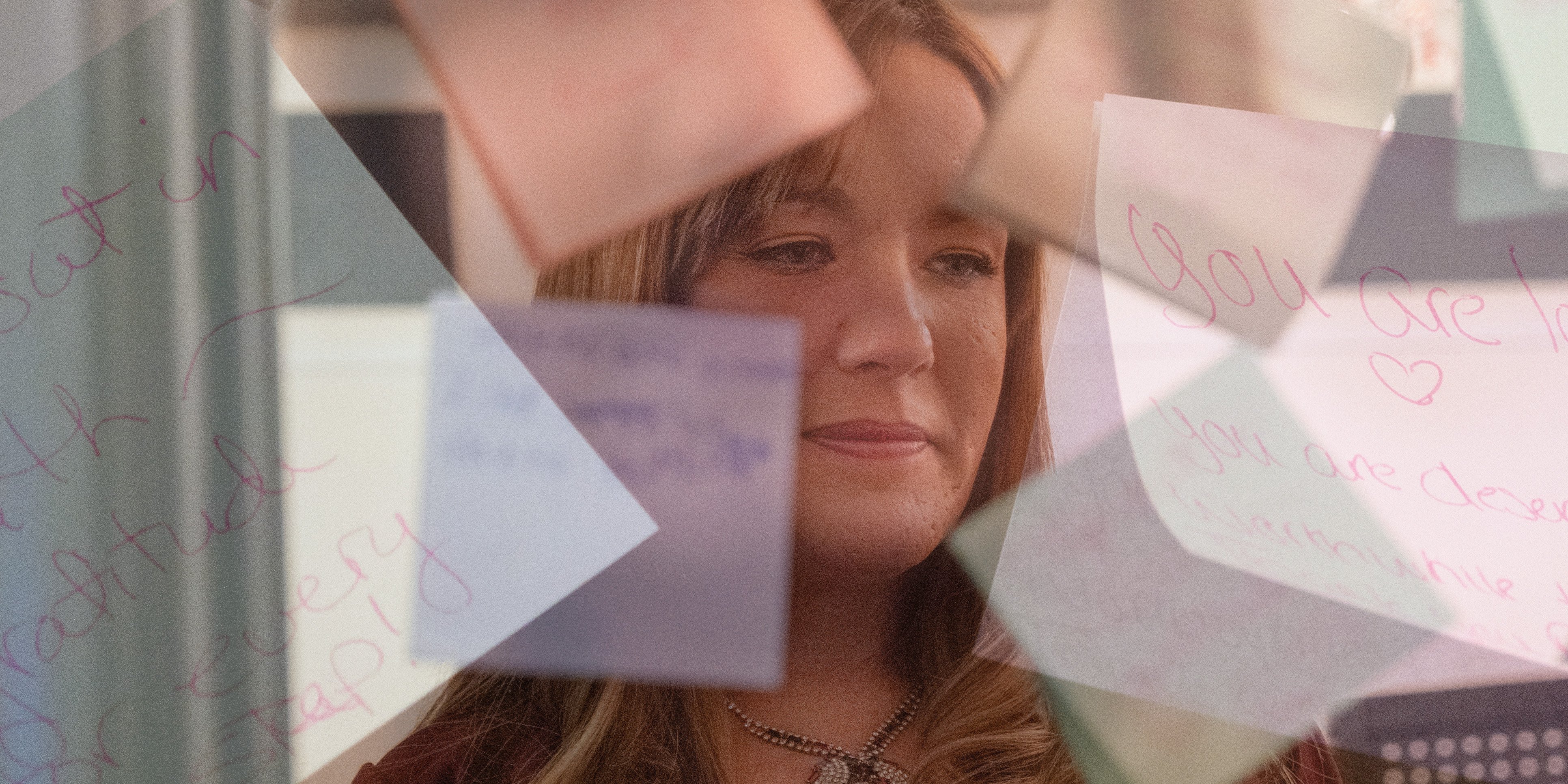A photo illustration shows Jodi Whitt reading notes of affirmation displayed at an exhibit of artwork created by program participants.