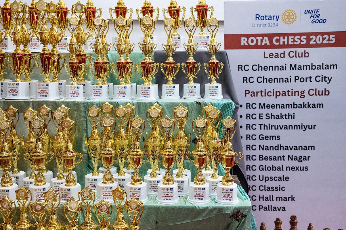 Trophies displayed beside a sign reading “ROTA CHESS 2025” listing participants and Rotary club organizers.