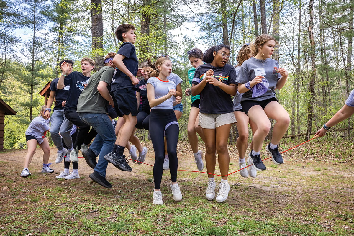As counselors spin a rope, team members coordinate with one another to jump in unison.