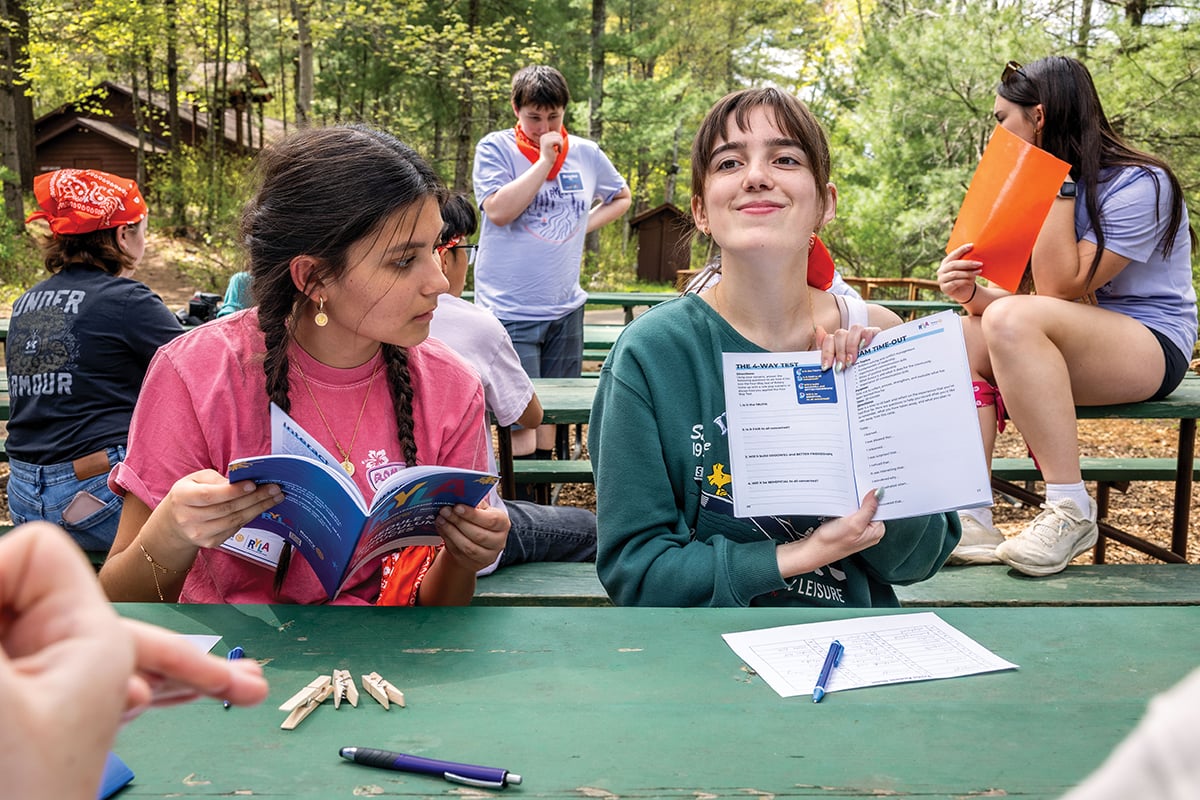 A participant displays a worksheet about The Four-Way Test in the program booklet.