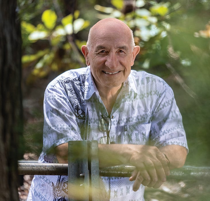 O rotariano Ross Smith, encostado em um corrimão ao ar livre, com árvores e folhagem ao fundo.