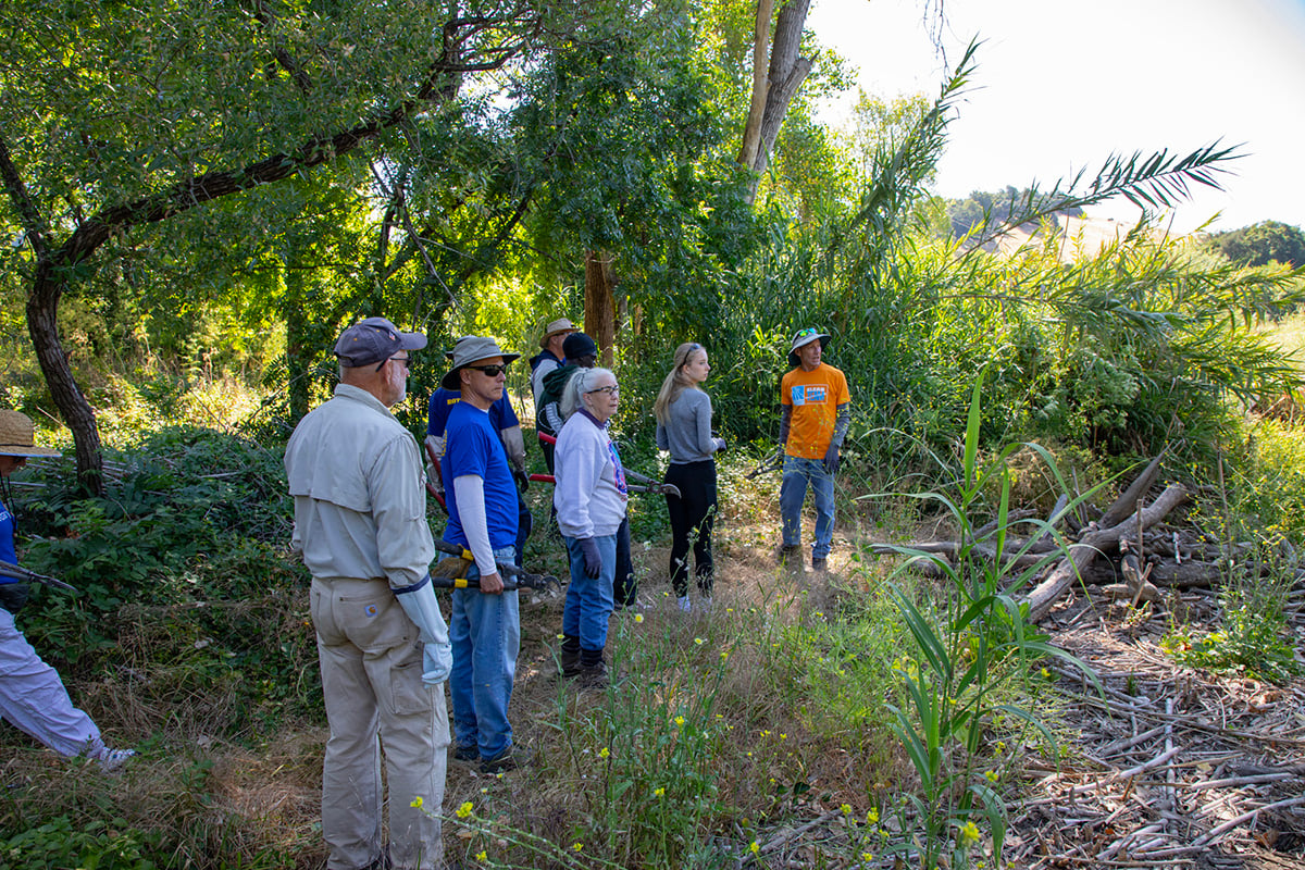Rotarians, Interactors, and other community members gather along a river