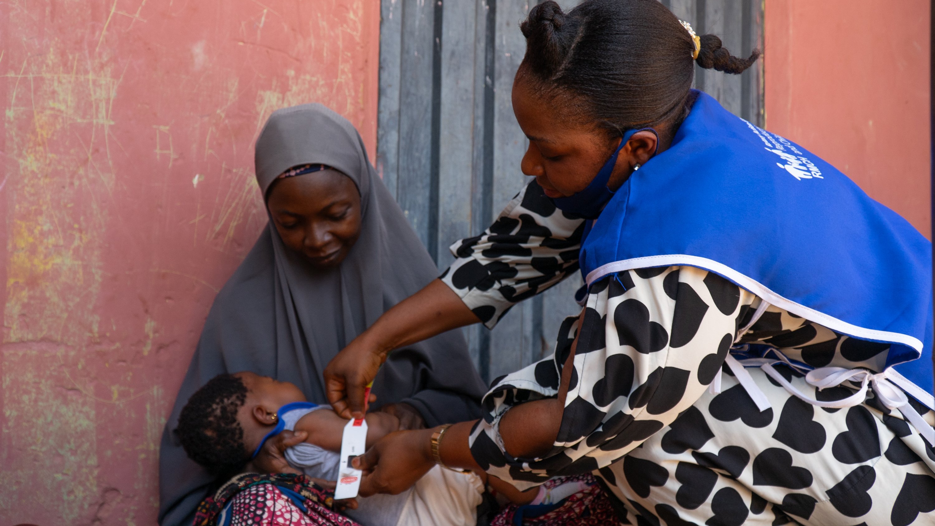Uma profissional de saúde presta assistência a Nafisa Abubakar e à sua filha, Halima Ode, em uma clínica em Nasarawa, na Nigéria, como parte da iniciativa “Juntos por Famílias Saudáveis” do Rotary.