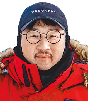 Young-sik Oh wearing a red cold-weather jacket and a navy hat displaying the word “DISCOVERY.”