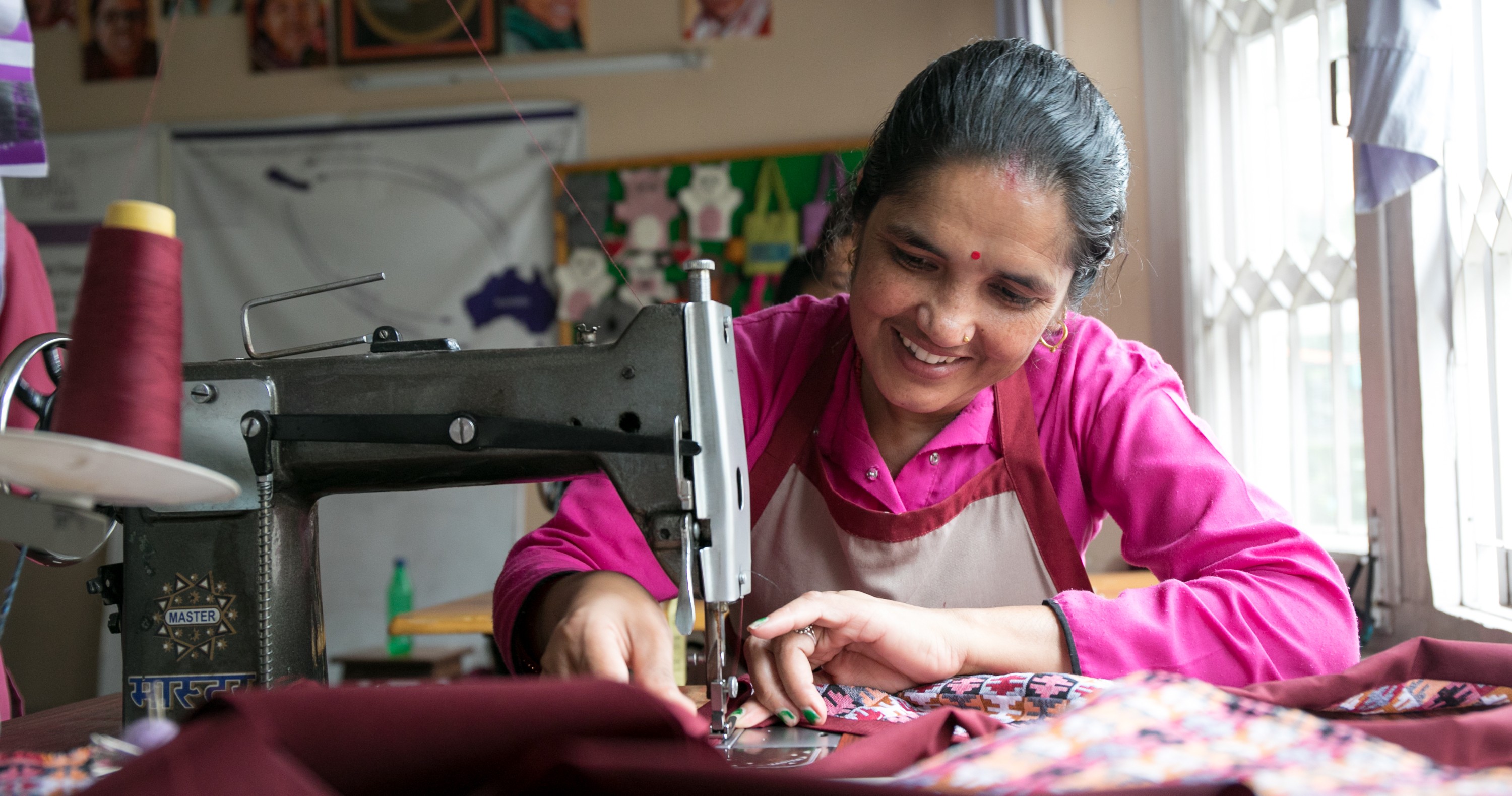 Une personne utilise une machine à coudre, guidant un tissu coloré tout en cousant dans un atelier.