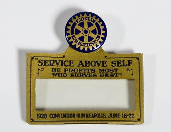 O crachá traz a inscrição “Dar de Si Antes de Pensar em Si”, com o emblema da roda do Rotary e a menção “Convenção de 1928 em Minneapolis, de 18 a 22 de junho”.
