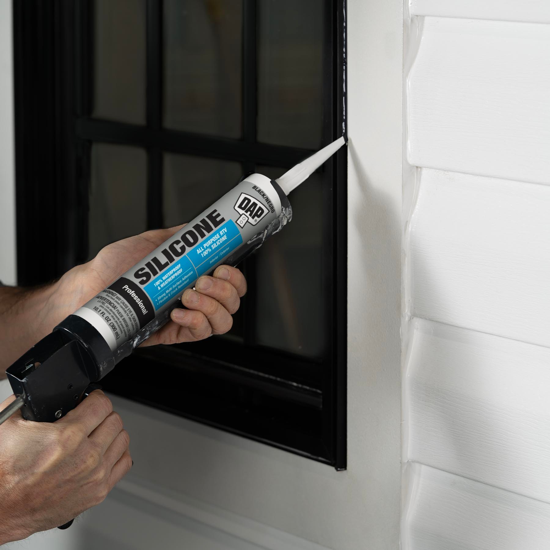 Industrial silicone sealant being applied to a black window frame