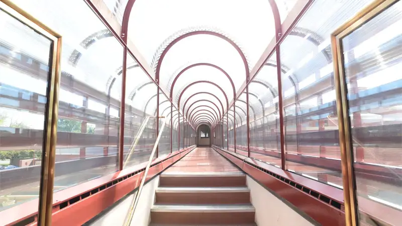Glass-covered walkway extending above street with arched roof