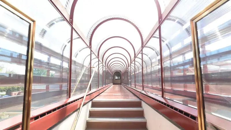 Une passerelle vitrée au-dessus de la rue avec un toit voûté