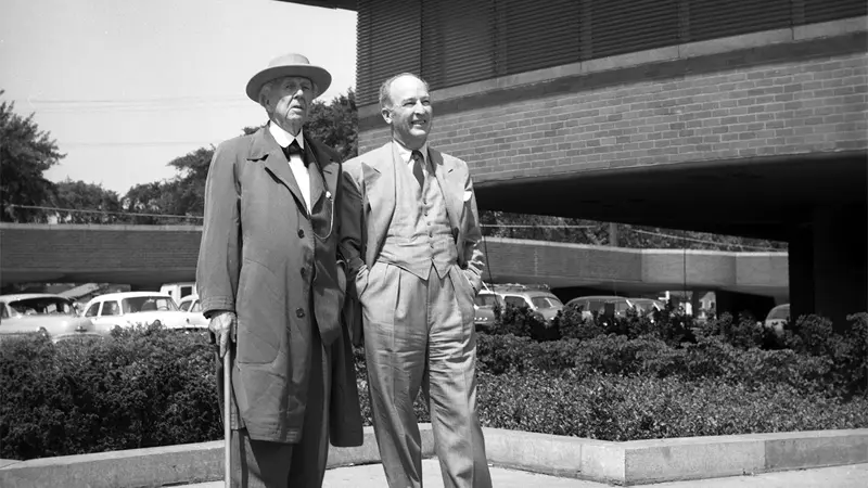 Two men standing, talking, outside a modern building