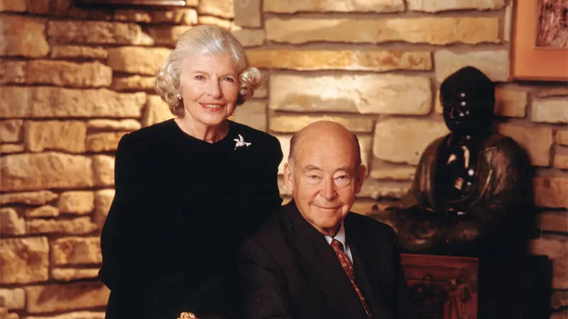 Elderly couple sitting together, surrounded by elegant, stone interior.