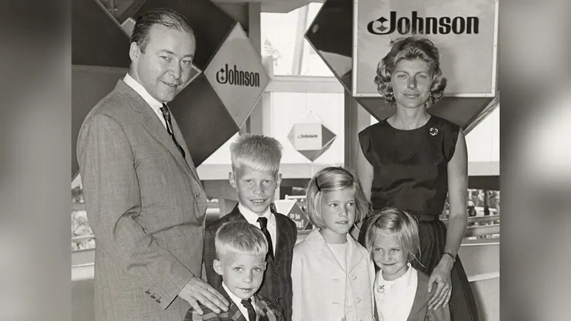 Family poses together indoors, surrounded by Johnson signage.