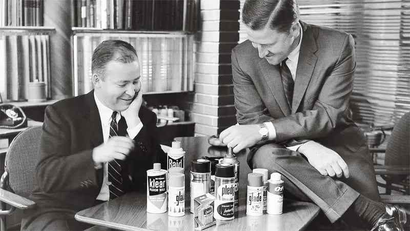 Two businessmen discussing products on a table; office background