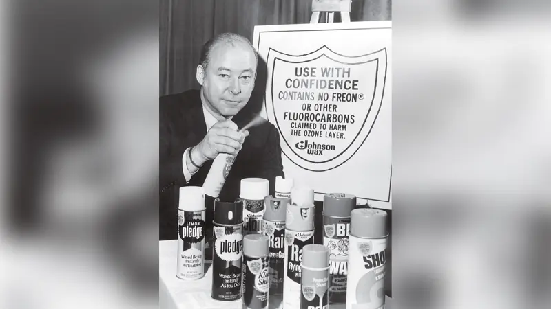 Man displaying cleaning products beside eco-friendly sign.