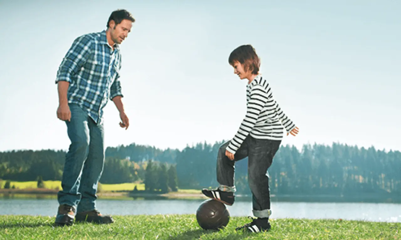 Padre e hijo juegan al fútbol afuera