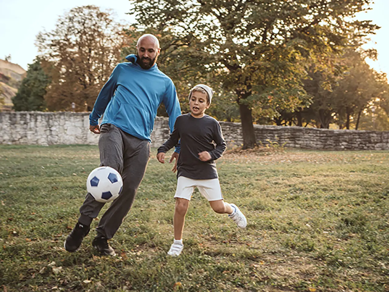 Parent and child playing soccer outdoors