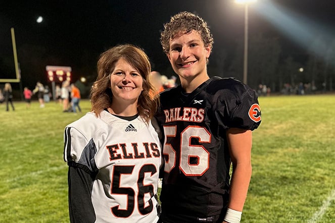 a child in a football uniform standing next to a woman on a football field