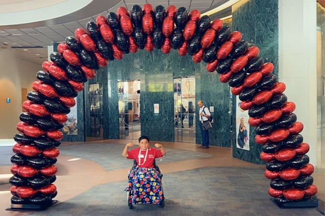 Carlitos bajo un arco de globos rojos y negros.