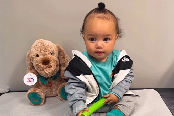 an infant sitting next to a plushie dog