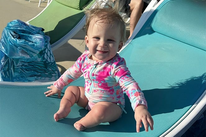 a young child sitting on a pool chair