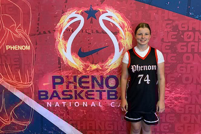 a child in a basketball uniform smiling in front of a colorful photo background