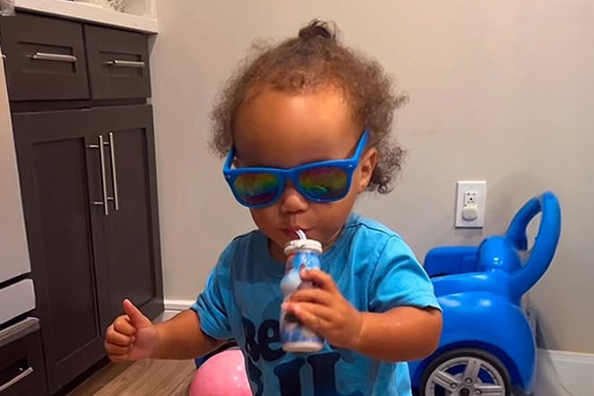 a toddler wearing sunglasses giving a thumbs up