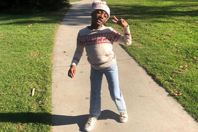 a child giving a peace sign on a sidewalk