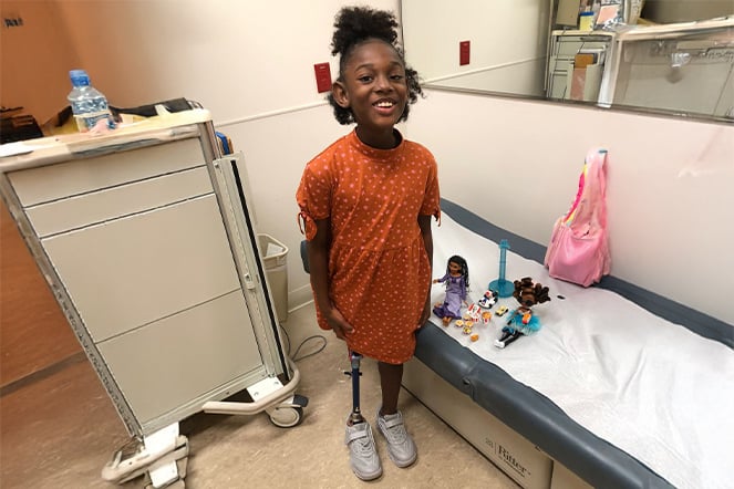 a smiling child wearing a prosthetic leg