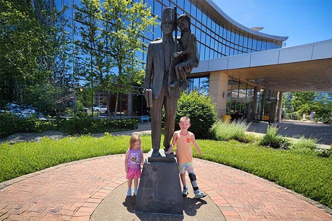 two young children stand around a large bronze statue