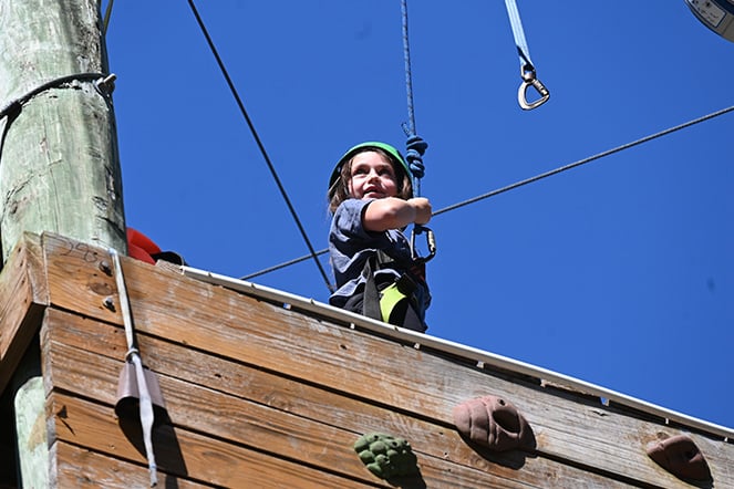 a young climber on top of a climbing wall