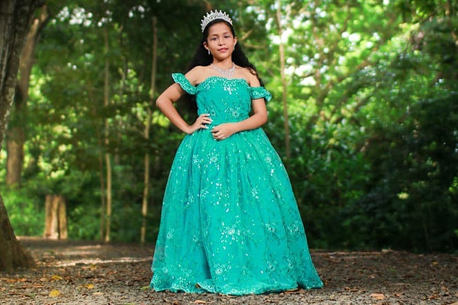 a child wearing an elegant gown standing in a forest