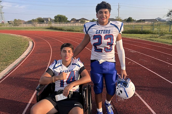 a child in a wheelchair next to their friend at a football game