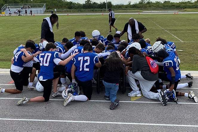 a football team kneeling together in a circle