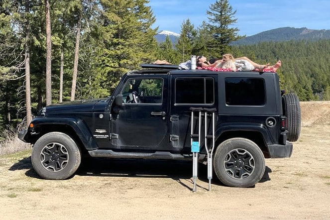 a woman and a god lying on top of a Jeep