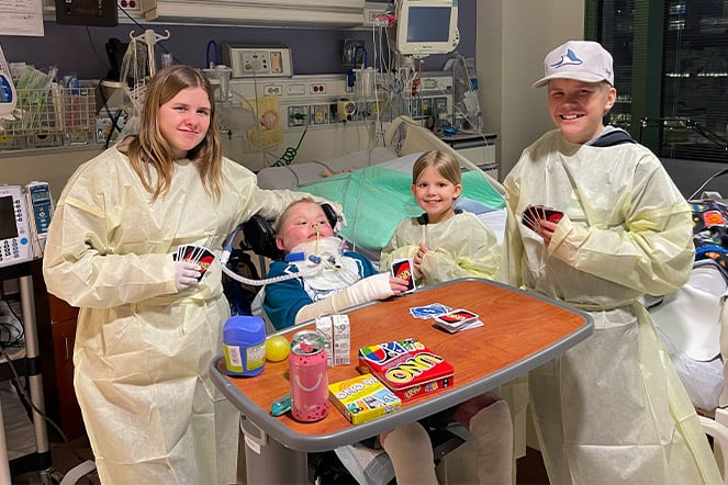 four children wearing hospital gowns playing a card game