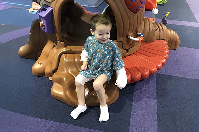 a child with wrapped hands and feet laughing and sitting in an indoor playground