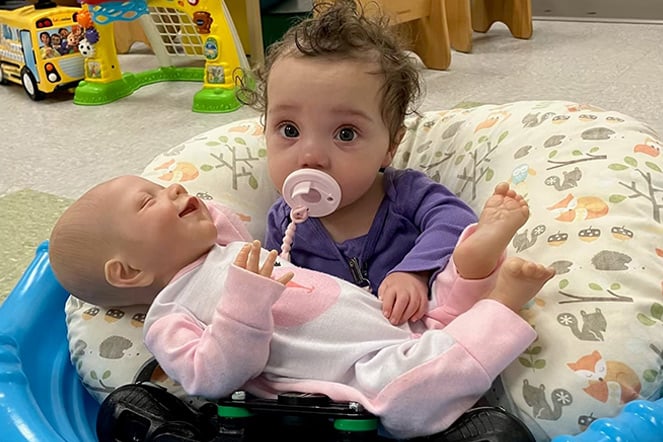 a baby with a pacifier holding a doll