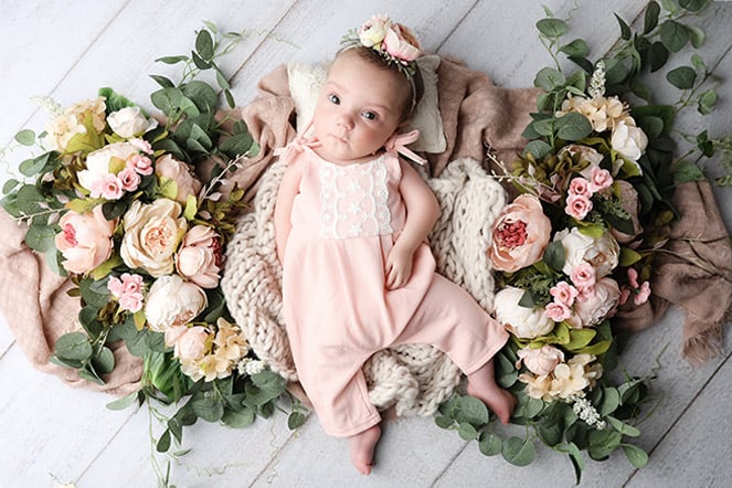 a baby lying on a blanket surrounded by flowers