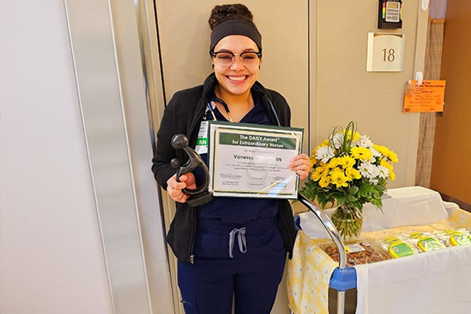 a nurse holding an award next to a vase of flowers