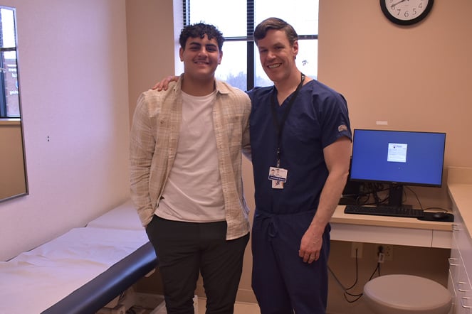 a doctor and a teenager smiling together in an examination room
