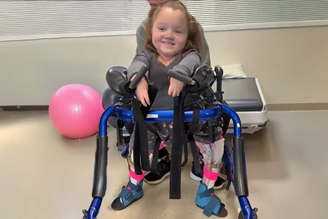 a young child standing in a weight-bearing physical therapy device
