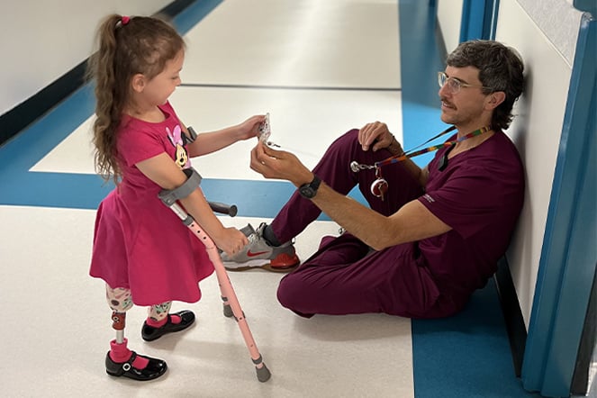 a child with crutches reads a sitting healthcare provider's name badge