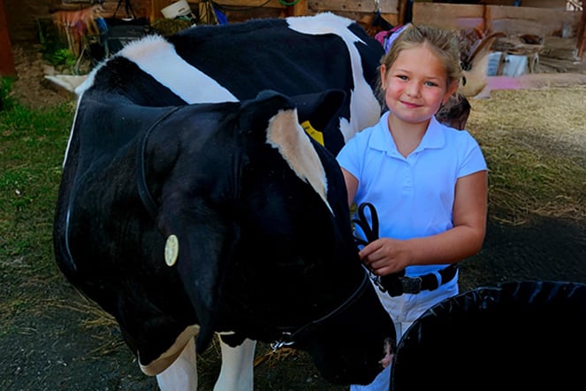 a child smiling next to a cow