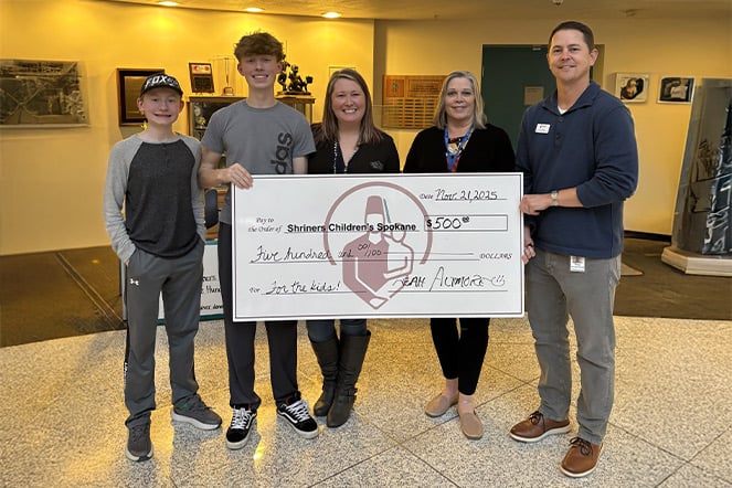 a family holding a large check with the Shriners Children's logo