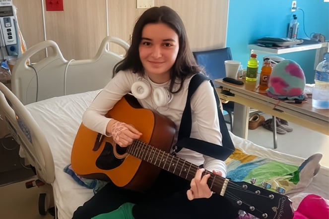 a child playing an acoustic guitar in a hospital bed