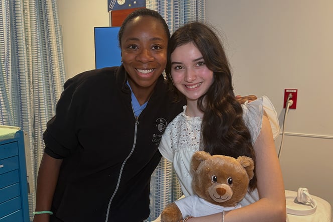 an adult woman next to a child holding a teddy bear