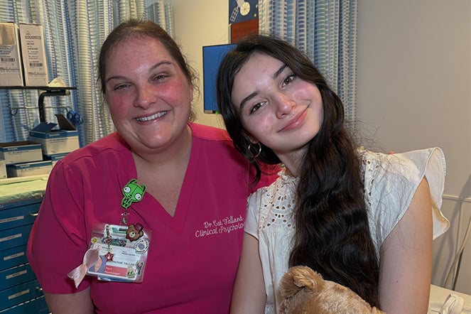 a woman in pink hospital scrubs smiling next to a teenage girl