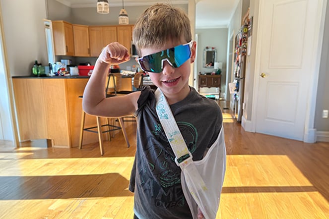 a child with his arm in a sling flexing his other arm