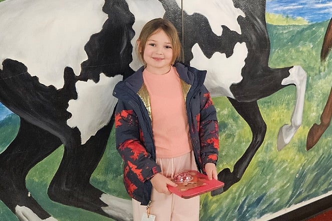 a child smiling in front of a mural of a horse